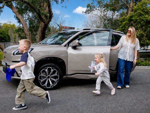 Family arriving at a shopping centre by car, with two children walking ahead as their mother steps out of the vehicle.